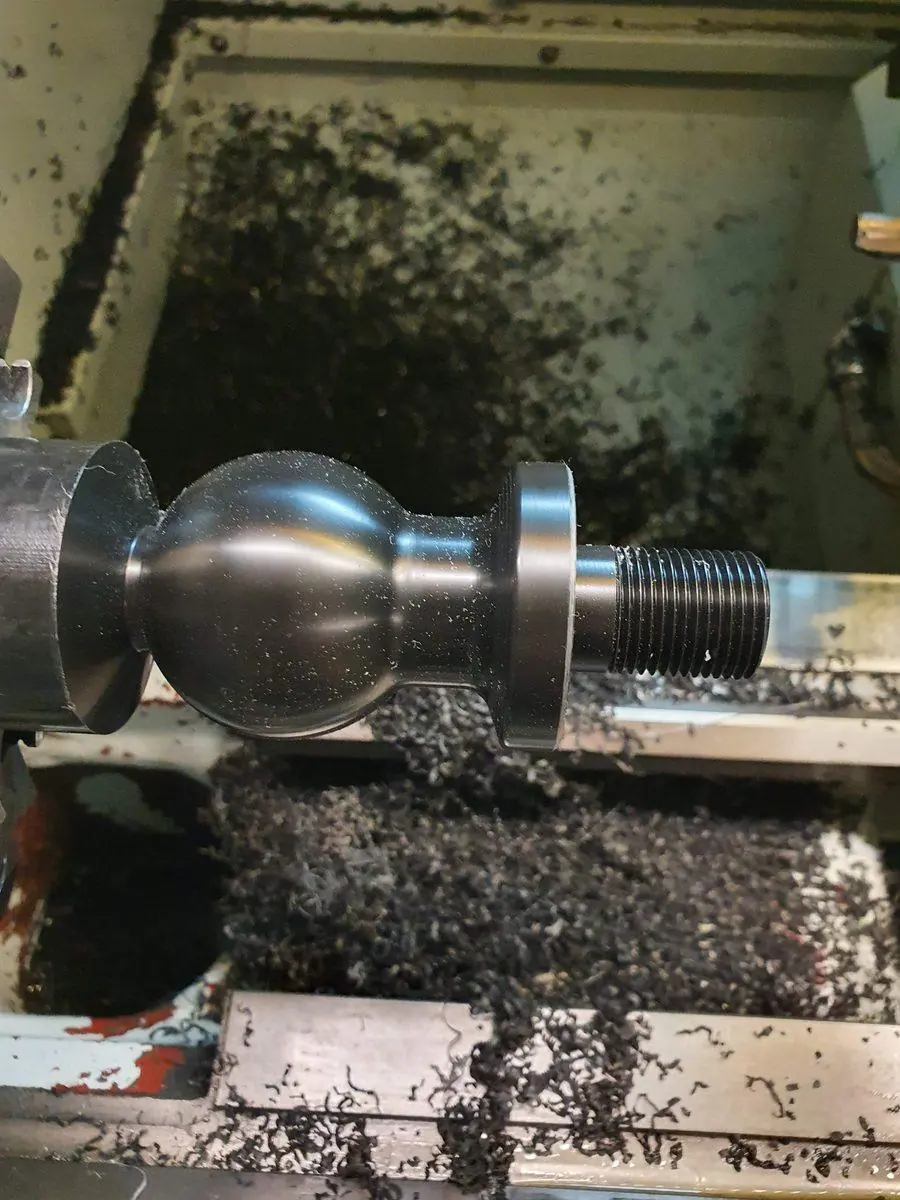 A ball form being turned on the lathe with swarf coming off the tool