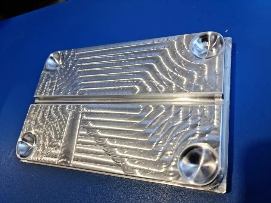 A machined aluminium plate with pocketed detail and a bright cut finish