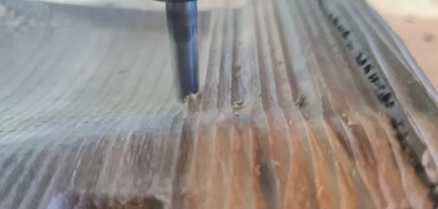 A reclaimed hardwood board part-way through a surfacing pass